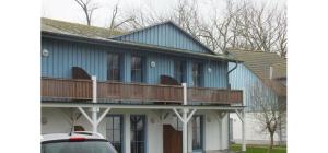 a blue house with a porch and a balcony at Ferienwohnung Rügen-Freiheit in Putgarten