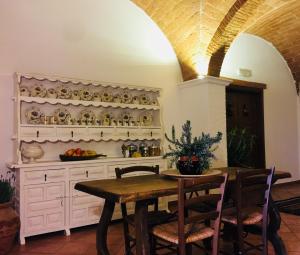 a dining room with a table and a shelf with dishes at Podere Casa Bianca in Santa Luce