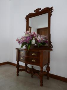 a dresser with a mirror and flowers on it at Villa Nilmalee in Gampola