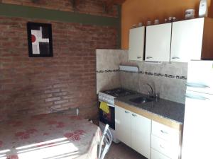 una cocina con armarios blancos y una pared de ladrillo en Ariel Reynoso - Departamento Planta Alta en Mina Clavero
