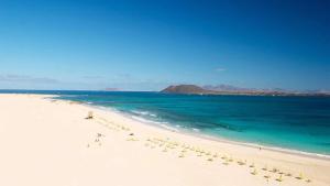 a beach with a group of people on the sand and the ocean at GBH Casa Quintana in La Oliva