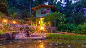 uma casa com uma parede de pedra ao lado de um lago em Sinharaja Hostel em Deniyaya