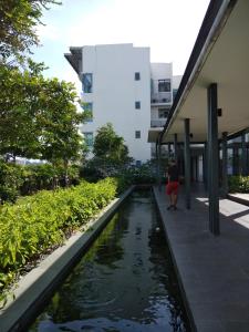 a woman standing next to a pond in front of a building at VH Homes, Imago Shopping Mall in Kota Kinabalu