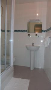 y baño blanco con lavabo y ducha. en Hotel des Vosges en París