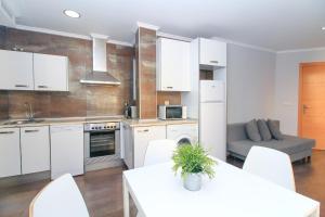 a kitchen with white cabinets and a table and a couch at BET Apartments - Tramontana Apartments in Valencia