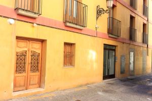 a yellow building with a wooden door on a street at BET Apartments - Tramontana Apartments in Valencia