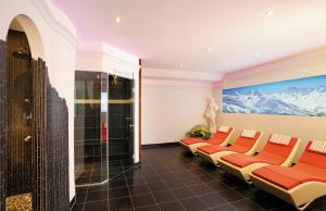 a waiting room with red chairs and a painting of mountains at Hotel Gramaser in Ischgl