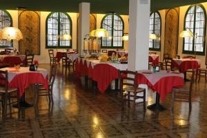 a dining room with tables and chairs with red table cloth at Hotel Le Cardinal in Bastiglia