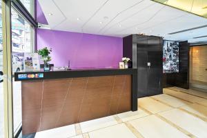 a lobby with a purple wall and a counter at Pop Inn Mong Kok in Hong Kong