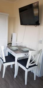 庫克斯港的住宿－Strandloft Cuxhaven im Haus Frauenpreiß，一张带两把椅子的白色桌子和墙上的电视