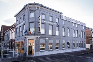 un grande edificio grigio all'angolo di una strada di Hotel New Flanders a Sint-Niklaas