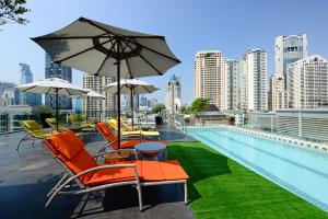 a pool with chairs and umbrellas on the roof of a building at Le D'Tel Bangkok in Bangkok