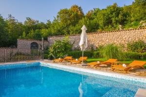 a swimming pool with chairs and an umbrella at Apartman Jurja in Ledenice