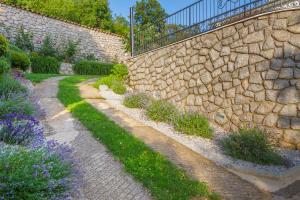 un jardin avec un mur en pierre et des fleurs violettes dans l'établissement Apartman Jurja, à Ledenice