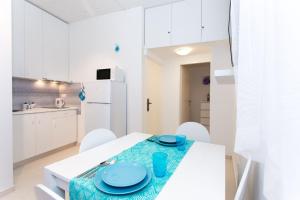 Korcula apartmanu Mili في كورتْشولا: مطبخ أبيض مع طاولة عليها لوحات زرقاء
