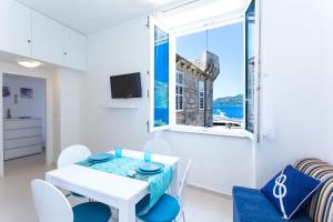 uma sala de jantar branca com uma mesa e cadeiras e uma janela em Korcula apartmanu Mili em Korčula