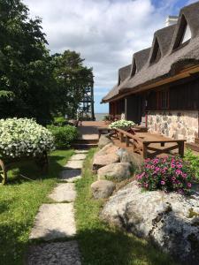 una casa con bancos y flores delante de ella en Tuulingu Guest House at Matsalu National Park, en Haeska