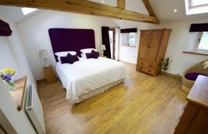 a bedroom with a large white bed and wooden floors at Saddleback View Cottage in Calthwaite