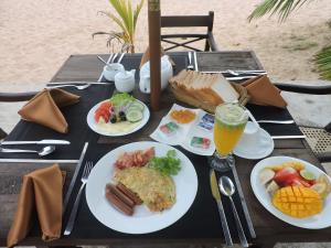 a table with plates of breakfast food and a glass of orange juice at Amanda Beach Villas in Unawatuna