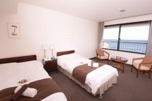 a hotel room with two beds and a large window at Isohara Seaside Hotel in Isohara