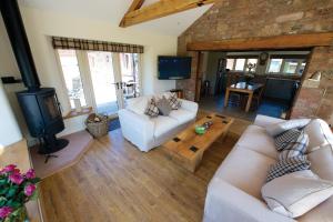 a living room with two white couches and a tv at Saddleback View Cottage in Calthwaite