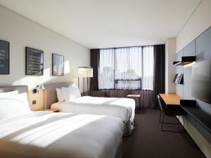 a hotel room with two beds and a desk at GLAD Mapo in Seoul