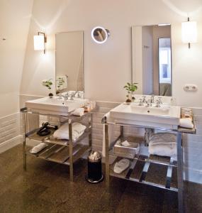 a white sink sitting under a mirror in a room at Louis Hotel in Munich