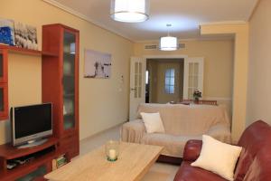 een woonkamer met een bank en een tv bij Villa Romana Roquetas in Roquetas de Mar