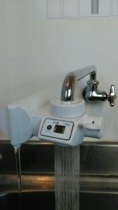 a water faucet with water coming out of it at Base Inn Komagome Tokyo in Tokyo