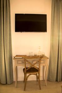 a wooden desk with a television on a wall with curtains at Casa al Mare Guest House in Swakopmund