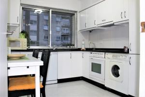 cocina con armarios blancos, lavadora y secadora en Apartamento Lula en Santiago de Compostela