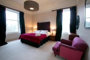 a bedroom with a bed and a purple chair at Eildonside in Melrose
