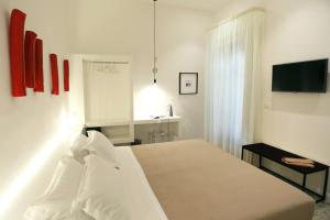 a white bedroom with a bed and a television at Re Ruggero Rooms in Reggio di Calabria