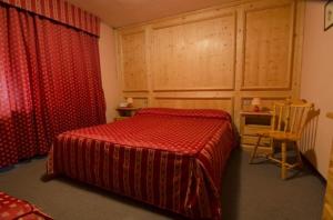 ガッリオにあるHotel Concordiaのベッドルーム(赤いベッド1台、椅子付)