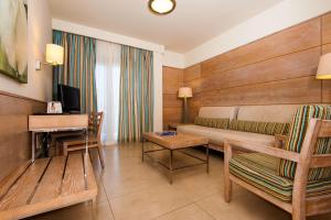 ein Hotelzimmer mit einem Sofa, einem Tisch und einem TV in der Unterkunft Kn Hotel Arenas del Mar Adults Only in El Médano
