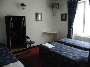 a hotel room with two beds and a window at Hôtel de la Gare in Saint Malo