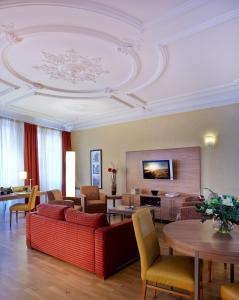 - un salon avec un canapé rouge et des tables dans l'établissement Citadines Kléber Strasbourg, à Strasbourg