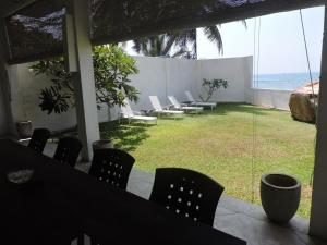 a patio with chairs and a view of the ocean at Galle Henna Beach House in Unawatuna