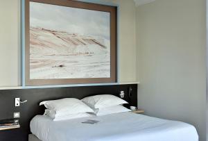 a bedroom with a bed with a picture above it at Hotel Spa Le Calendal in Arles