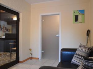 een woonkamer met een bank en een deur bij Cozy Apartment in County of Manderscheid with TV in Manderscheid