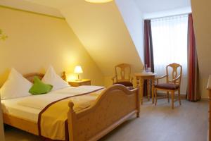 ein Hotelzimmer mit einem Bett, einem Tisch und Stühlen in der Unterkunft Hotel Speeter in Weisenheim am Berg