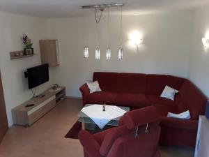 ein Wohnzimmer mit einem roten Sofa und einem TV in der Unterkunft Haus Edzards in Neuharlingersiel