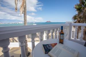 Una botella de vino y un libro en un balcón con la playa en Galera Beach Apartamentos, en Corralejo