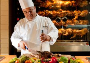 a chef preparing food on a cutting board in a kitchen at Leonardo Club Tiberias - All Inclusive in Tiberias