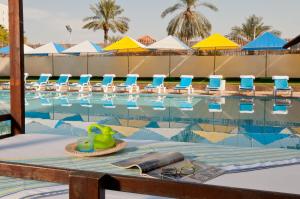 a swimming pool with chairs and a table with a drink at Leonardo Club Tiberias - All Inclusive in Tiberias