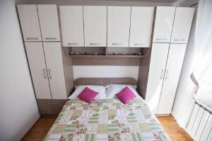 a bedroom with a bed with white cabinets and pink pillows at Apartment Green Oasis in Split