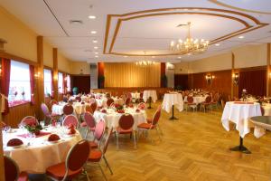 une salle de banquet avec des tables, des chaises et un lustre dans l'établissement Röhrs Gasthof, à Sottrum