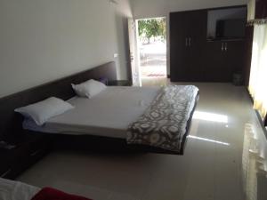 een slaapkamer met een groot bed met witte lakens bij Hiran Holidays in Sasan Gir