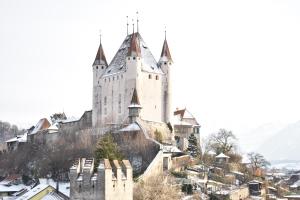 ein Schloss auf einem Hügel mit Schnee darauf in der Unterkunft Hotel AM Schloss in Thun