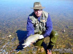 a man holding a fish in a body of water at Cabañas Malleo in Junín de los Andes